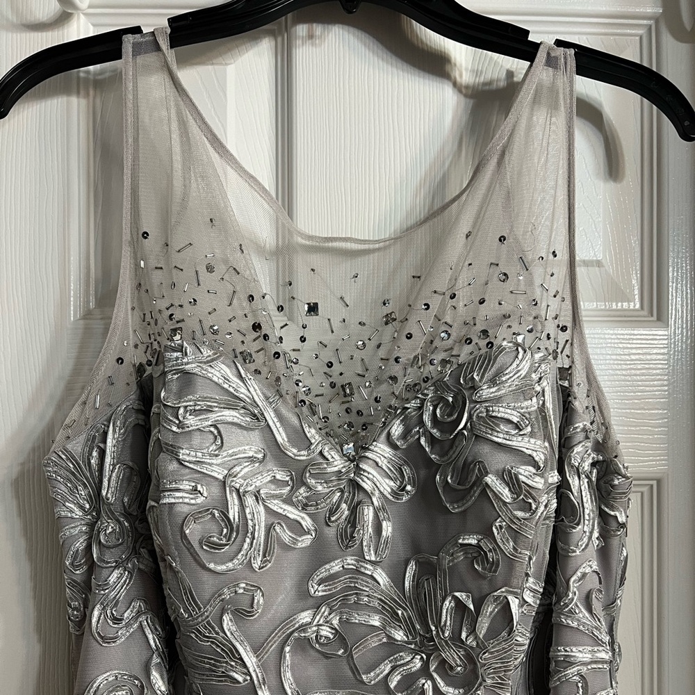 Silver formal gown with sleeveless design and jeweled top.